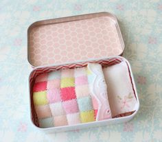 an open tin with some towels in it on a floral table cloth covered tablecloth