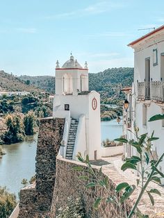 an old church on the side of a hill next to a body of water