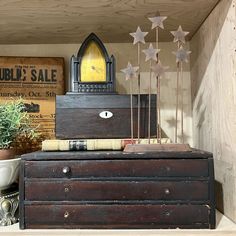 an old chest with books and plants on top in a room filled with antiques, signs and other items