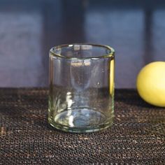 an empty glass next to a lemon on a table