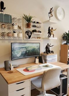 a desk with a computer on top of it next to a clock and shelves filled with figurines