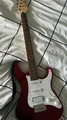 a red electric guitar laying on top of a bed