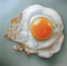 an egg is in the shape of a broken shell on a blue surface with water droplets around it