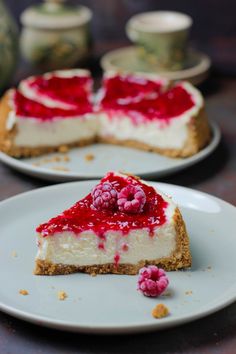 there is a piece of cheesecake with raspberry topping on the plate next to it