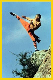 a man in an orange outfit is doing a kickbox on top of a rock