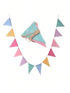 a paper kite is hanging from a string on a white wall with colorful triangles around it