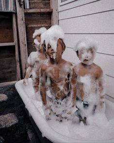 three children covered in foam sit on a sled with snow all over their bodies