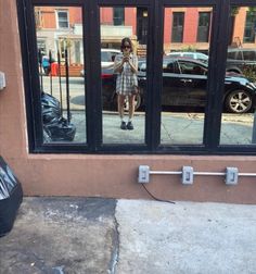 a woman taking a selfie in the window of a building with her cell phone