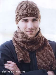 a young man wearing a knitted hat and scarf with his arms crossed in front of him