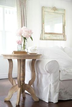 a living room with white furniture and flowers on the table