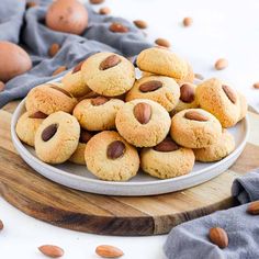 almond cookies on a plate with nuts scattered around