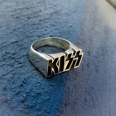 a silver ring with the word kiss on it sitting on top of a blue surface