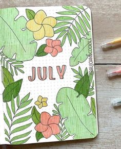 a notebook with the word july written on it next to some markers and pencils