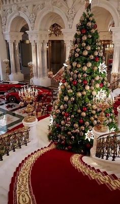 a christmas tree in the middle of a room with red carpet and gold trimmings