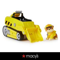 a yellow toy bulldozer next to a small dog on a white background with the words macy's written below it