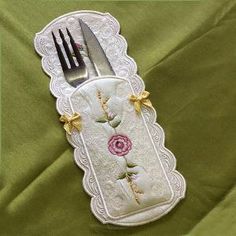 the fork and knife holder is made out of white fabric with pink roses on it