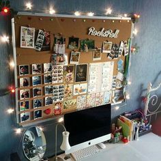 a desk with a computer on it and lots of pictures attached to the back wall