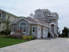 a large house sitting on top of a lush green field next to a sidewalk and grass covered yard