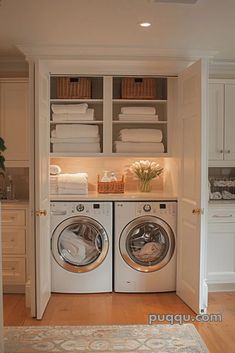 a washer and dryer in a small room with white cabinets on either side