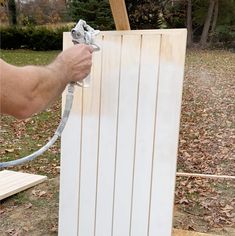 a man is using a hose to spray paint the side of a wooden structure with wood planks