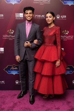 two people standing next to each other on a purple carpet