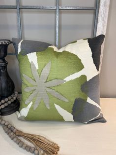 a green and white pillow sitting on top of a bed next to a black vase