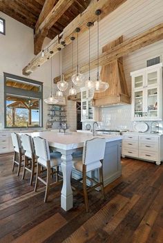 a large kitchen with wooden floors and white cabinets, along with lots of lights hanging from the ceiling