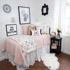 a white and black bedroom with pink bedding, pillows and pictures on the wall