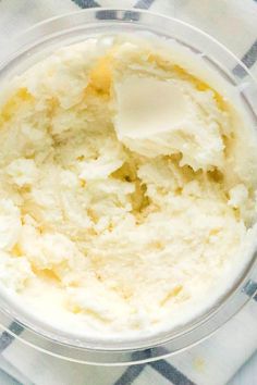 a bowl filled with mashed potatoes on top of a checkered table cloth