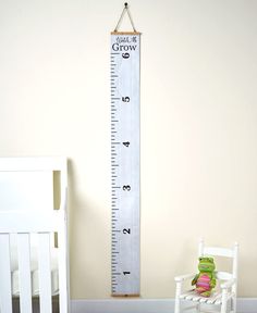 a white wooden growth chart in a child's room with a rocking chair next to it