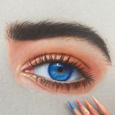 a drawing of an eye with colored pencils in front of it and the image of a person's face