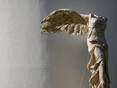 an angel statue is standing next to a wall