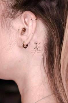 a woman's ear has a small flower tattoo on it