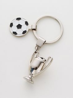 a soccer trophy keychain with a ball on it and a cup in the middle