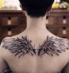 the back of a woman's neck with black wings on her upper half and chest