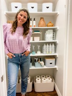 a woman standing in front of an open refrigerator with lots of toiletries on the shelves