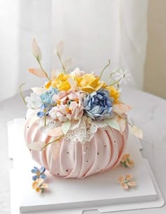 a pink pumpkin decorated with flowers on top of a white table next to a window