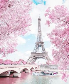 the eiffel tower is surrounded by pink trees and boats on the river below