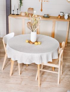 a white table with two chairs and a vase filled with flowers on top of it