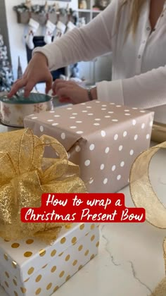 a woman opening a present box with a gold bow on it and the words how to wrap a christmas present low