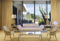 a living room filled with lots of furniture and large windows overlooking the cactus covered area