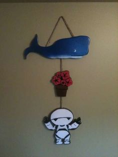 a blue whale hanging from the side of a wall next to a red flower pot