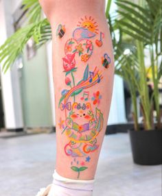 a woman with colorful tattoos on her legs and leggings is standing in front of a potted plant