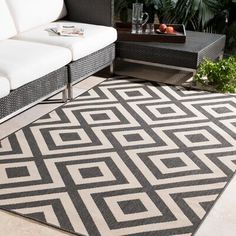 a black and white area rug on the ground near a couch, coffee table and potted plant