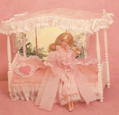 a barbie doll sitting on top of a bed with a pink canopy over it's head