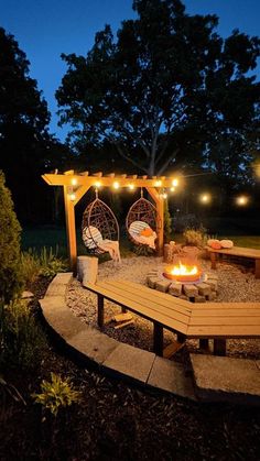 an outdoor fire pit with lights strung around it and some chairs in the background at night