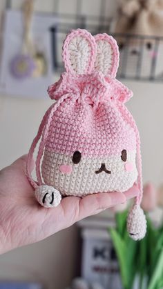 a hand holding a small crocheted bag with a bunny face on the front