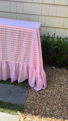 a pink and white checkered table cloth sitting on the ground next to a house