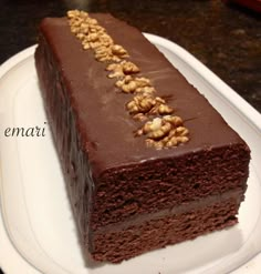 a piece of chocolate cake with walnuts on top sitting on a white platter