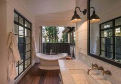 a bathroom with two sinks and a bathtub in the middle, along with large windows